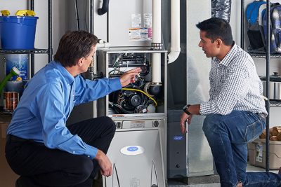 HVAC technician explaining furnace repair and maintenance to a homeowner in Pleasant Grove, UT